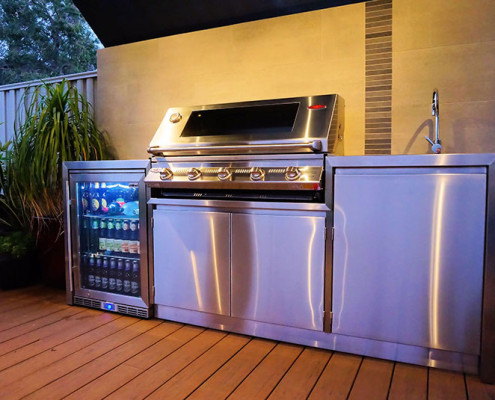 A stainless steel barbecue with sink & bar fridge