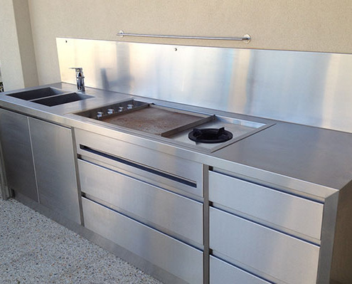 A stainless steel outdoor kitchen with cooktop, hot plate & double sink