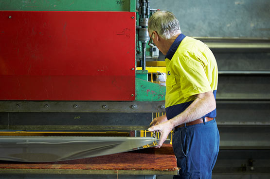 A Metro Steel Services team member working with a sheet of stainless steel
